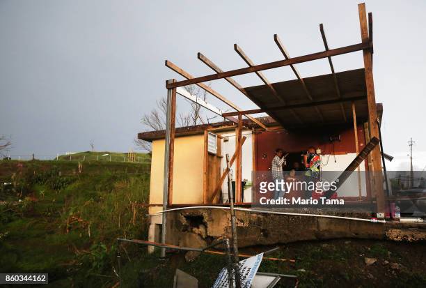 Men gather at a partially destroyed bar three weeks after Hurricane Maria hit the island, on October 11, 2017 in Aibonito, Puerto Rico. The area is...