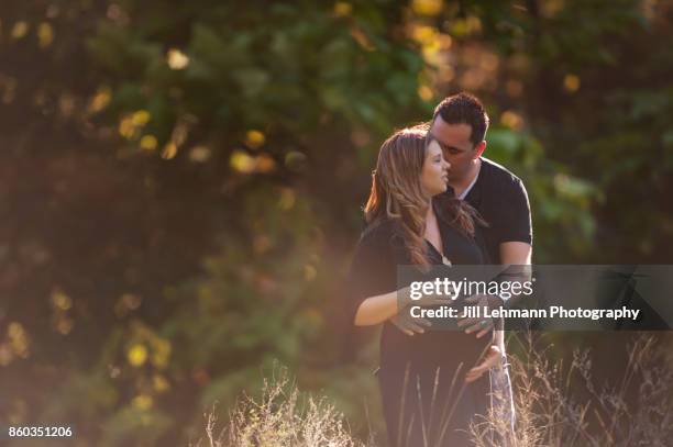 golden sun drenched maternity session of expectant mother and father of twins - sun flare couple stock-fotos und bilder