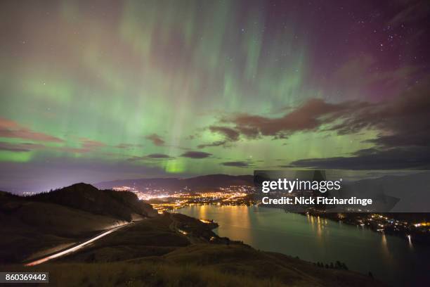 the green pillars of an aurora borealis above the lights of coldstream and vernon, north okanagan, british columbia, canada - okanagan valley stock-fotos und bilder