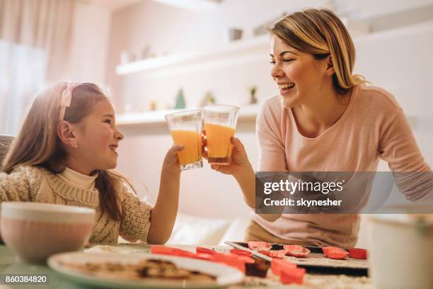 felice madre e figlia che brindano con succo durante la cottura. - family orange juice foto e immagini stock