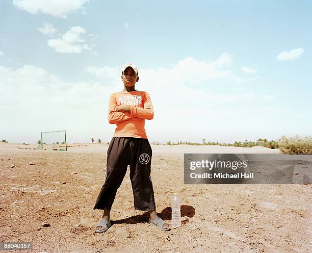 boy standing in barren football field - documentaire stockfoto's en -beelden