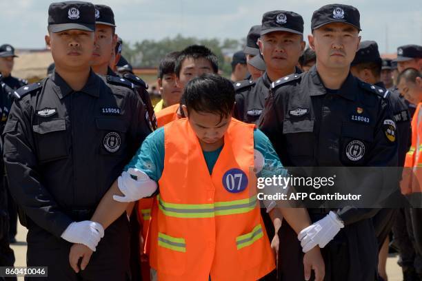 Chinese police escort suspects to a plane at Phnom Penh international airport on October 12, 2017. Cambodia deported 74 Chinese national suspected of...