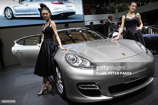 Models pose next to a Porsche Panamera, a new four-door sports car making its international debut at Auto Shanghai 2009, China's largest auto show on...