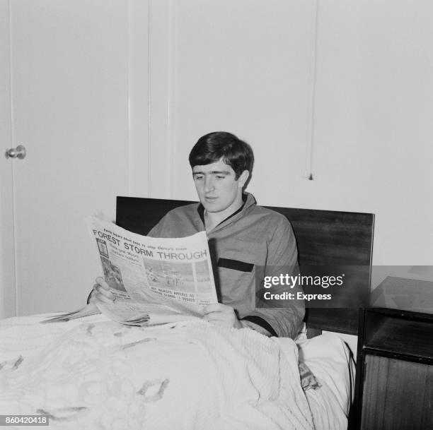 English soccer player Ian Storey-Moore of Nottingham Forest FC, lying in bed while reading a newspaper titled 'Forest storm through', UK, 10th April...