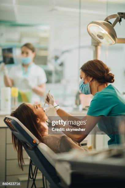 young woman having her teeth checked during dental appointment at dentist's office. - dentista imagens e fotografias de stock