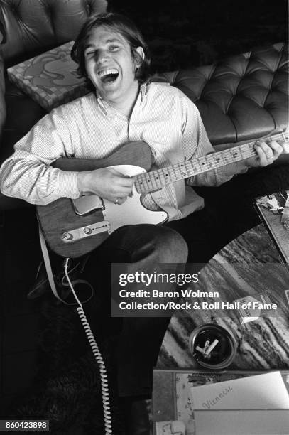 Portrait of Jann Wenner, founder and publisher of Rolling Stone magazine, playing a Fender Telecaster guitar at home in San Francisco, 1969.