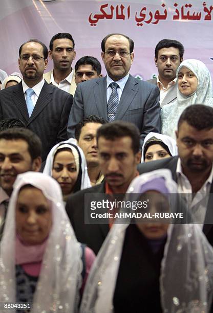 Iraqi Prime Minister Nuri al-Maliki stands for a group photo with the relatives of Iraqis killed during the regime of former Iraqi president Saddam...