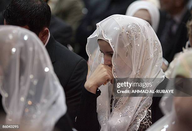 An Iraqi newly wed sits listening to Iraqi Prime Minister Nuri al-Maliki as he gives a speech to relatives of Iraqis killed during the regime of...