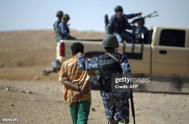 Iraqi police officers of the Anbar 8th Battalion arrest a local man during their patrol in the Hurran Valley near the town of Haditha, 260 kms...