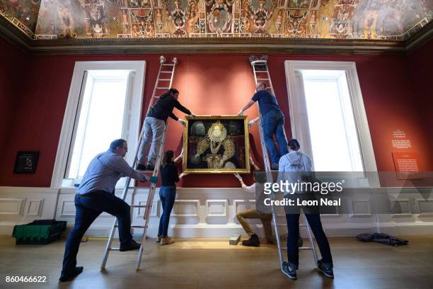 Gallery assistants pose with the "Armada Portrait of Elizabeth I" oil painting as it is unveiled following extensive cleaning at the Queen's House,...