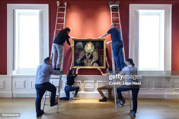 Gallery assistants pose with the "Armada Portrait of Elizabeth I" oil painting as it is unveiled following extensive cleaning at the Queen's House,...