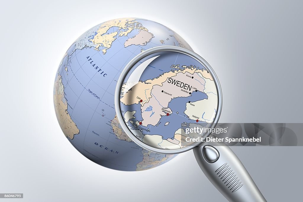 Reading glass shows Sweden on a globe closeup