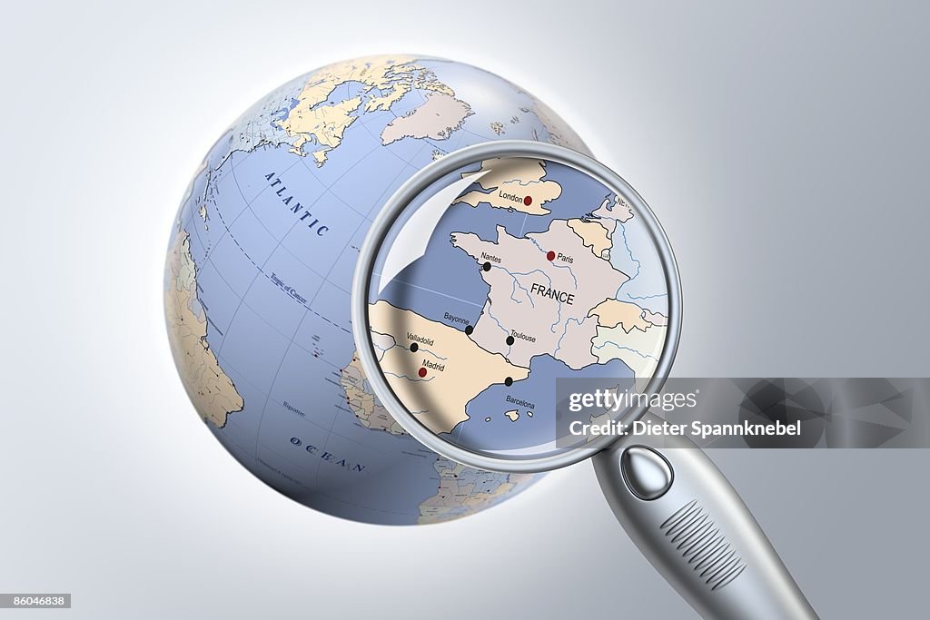 Reading glass shows France on a globe closeup