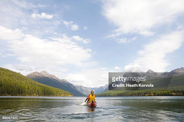 a young woman kayaking on a lake. - us glacier national park stockfoto's en -beelden