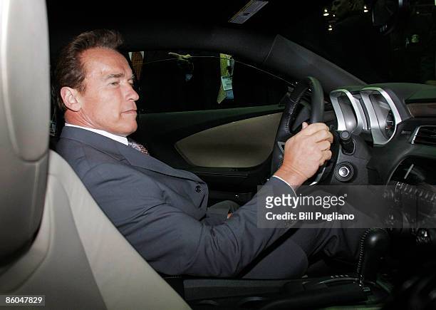 California Governor Arnold Schwarzenegger sits in the driver's seat of a Chevy Camero while touring the exhibits of the 2009 Society of Engineers...