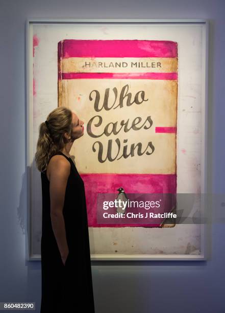 Woman poses for photographs next to Who Cares Wins by Harland Miller, estimated at £20,000-£25 during an Art for Grenfell press call at Sotheby's Art...