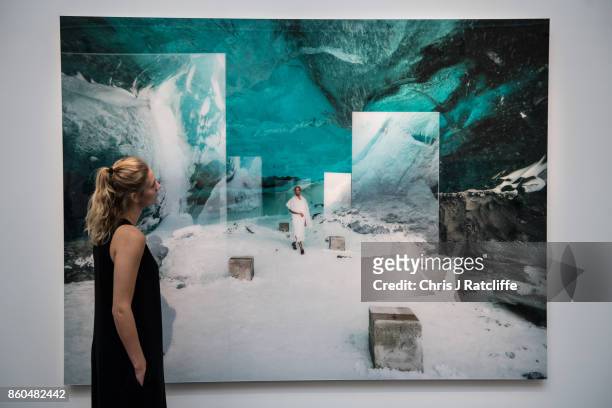 Woman poses for photographs next to En Passage by Isaac Julien, estimated at £18,000-£25 during an Art for Grenfell press call at Sotheby's Art for...