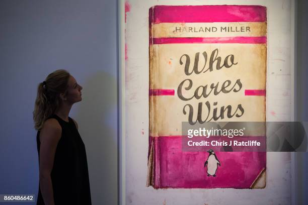 Woman poses for photographs next to Who Cares Wins by Harland Miller, estimated at £20,000-£25 during an Art for Grenfell press call at Sotheby's Art...
