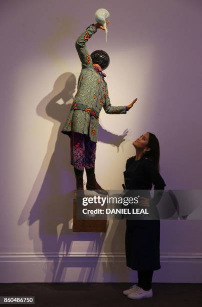 Gallery employee poses in front of an artwork entitled 'Bad School Boy' 2014, by British-born Nigerian artist Yinka Shonibare, during a photocall for...