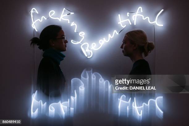 Gallery employees pose in front of an artwork entitled 'fuckingbeautiful 2013' by Britsih artists Tim Noble and Sue Webster, during a photocall for...