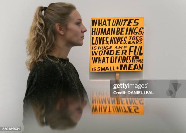 Gallery employee poses in front of an artwork entitled 'What Unites Human Beings' 2017, by British artist Bob and Roberta Smith, during a photocall...