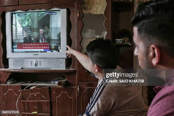 Palestinians watch on TV the signing of a reconciliation deal in Cairo between rival Palestinian factions Hamas and Fatah on October 12 in Rafah in...