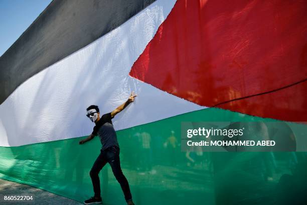 Palestinian youth poses in front of his national flag during celebrations in Gaza City after rival Palestinian factions Hamas and Fatah reached an...