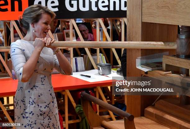 Queen Mathilde of Belgium works a so-called Gutenberg printing press as she visits the French pavillion at the Frankfurt Book Fair 2017 in Frankfurt...