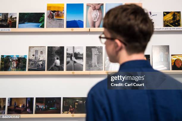Member of staff poses next to photograph postcards featuring images by photographers including Martin Parr and Wolfgang Tillmans ahead of a secret...