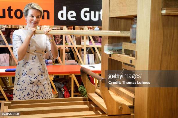 Queen Mathilde of Belgium prints the declaration of the human rights with and an old print press at the pavilion of the French guest of honour at the...