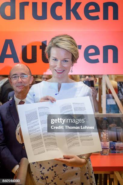 Queen Mathilde of Belgium shows the declaration of the human rights that was printed with an old print press at the pavilion of the French guest of...