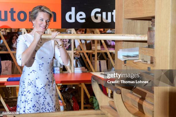 Queen Mathilde of Belgium prints the declaration of the human rights with and an old print press at the pavilion of the French guest of honour at the...