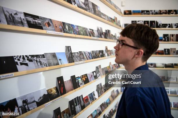 Member of staff poses next to photograph postcards featuring images by photographers including Martin Parr and Wolfgang Tillmans ahead of a secret...