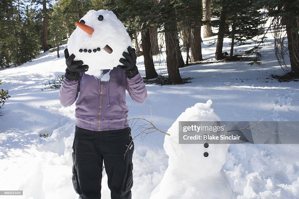 Woman holding snowman head in front of face