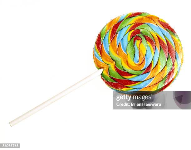 rainbow swirl lollipop on white - lolly stockfoto's en -beelden