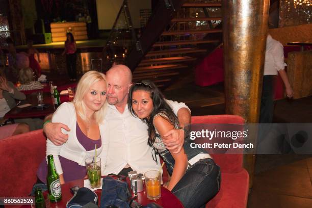 Man poses for a photograph with two young Ukranian women he met at a social event organised by The Anastasiaweb.com Experience at The Palladium Club,...