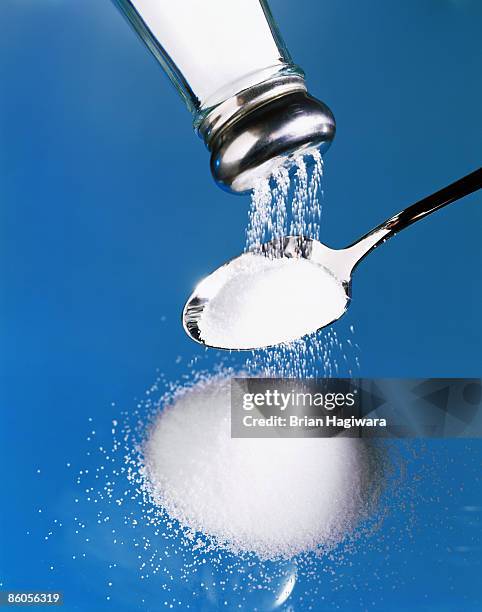 salt pouring into spoon - gesalzenes stock-fotos und bilder