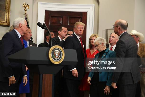 Secretary of Labor Alexander Acosta taps on the shoulder of U.S. President Donald Trump to remind him to sign an executive order after his remarks as...