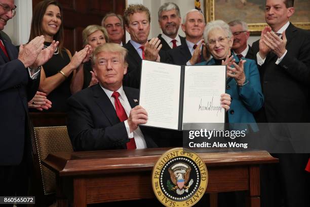 President Donald Trump shows an executive order after he signed it as Sen. Rand Paul , Vice President Mike Pence, Rep. Virginia Foxx and Secretary of...