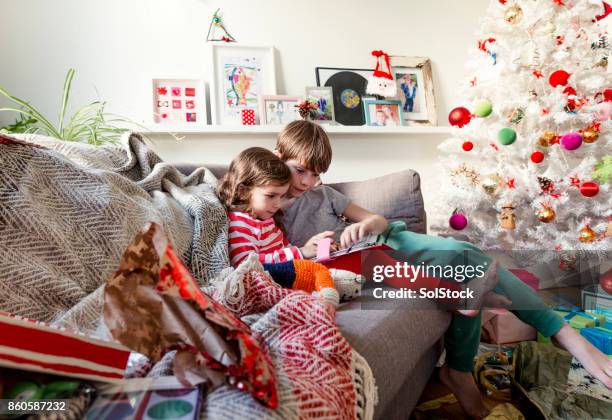 siblings sharing a digital tablet - christmas toys stock pictures, royalty-free photos & images