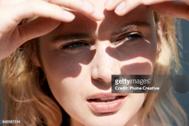 woman shielding eyes from sun - queimadura pele - fotografias e filmes do acervo
