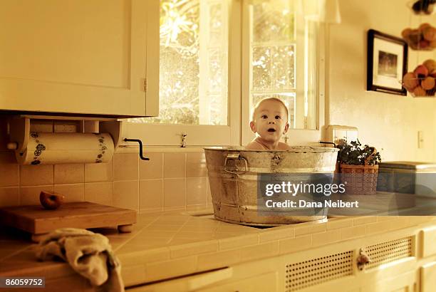 baby in washtub on kitchen counter - zinkwanne stock-fotos und bilder