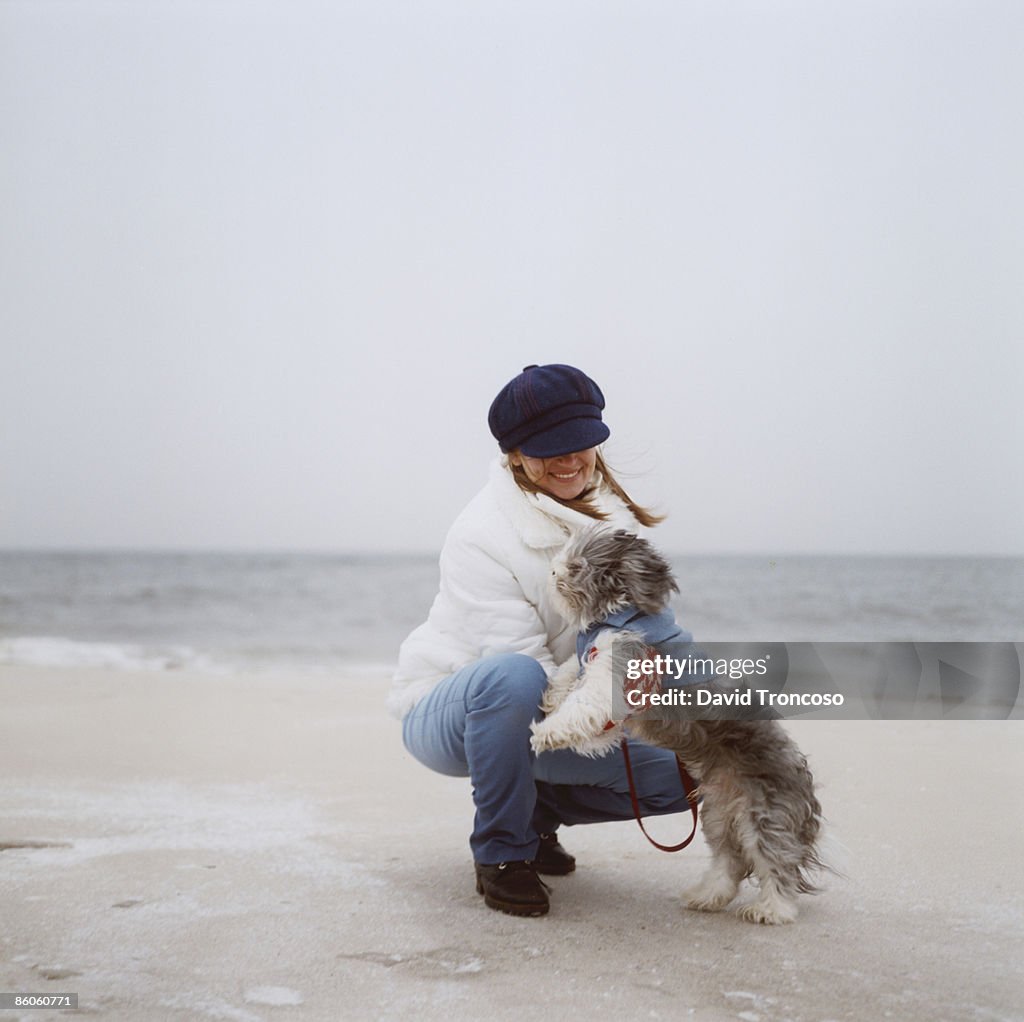 Woman playing with dog on beach