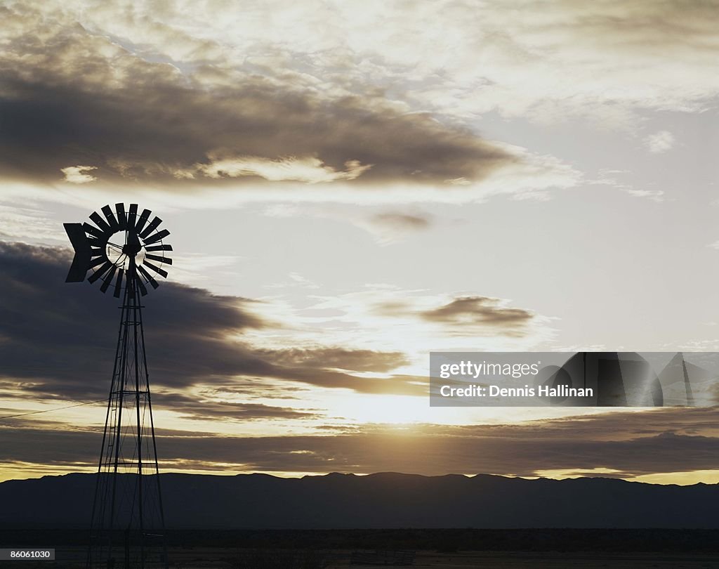 Windmill in field at sunset