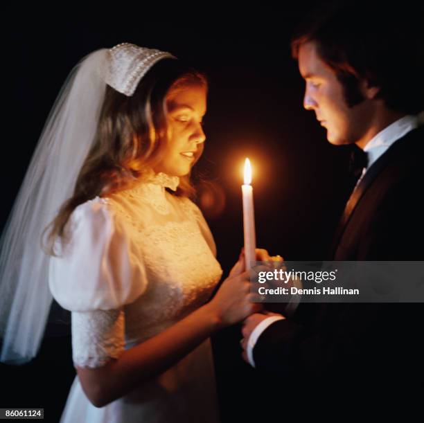 Bride and groom holding candle in the dark