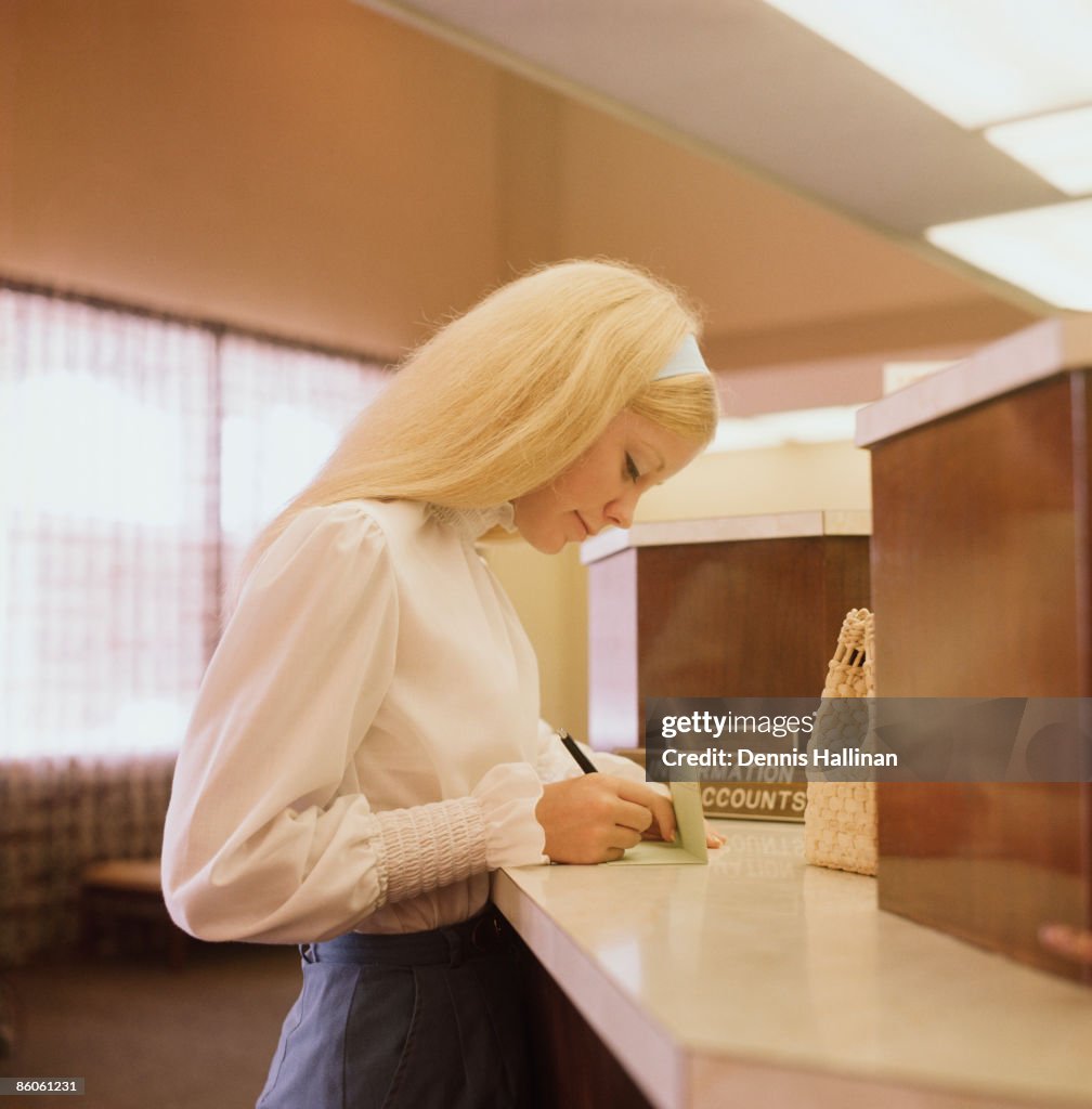 Woman making deposit at bank service counter