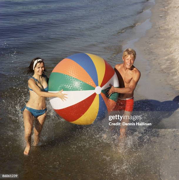 Couple running in ocean and playing with beach ball