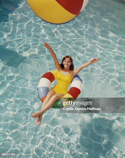 Woman relaxing in pool float tossing beach ball