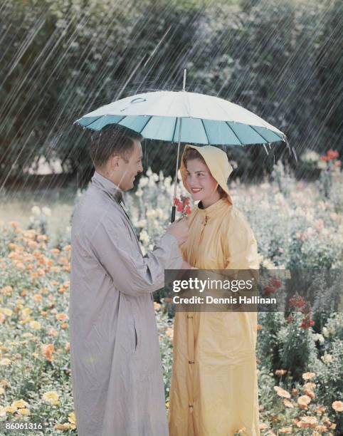 Retro couple standing in flower field in the rain