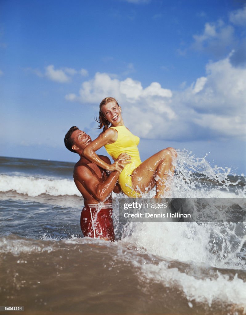 Playful retro couple splashing in the surf